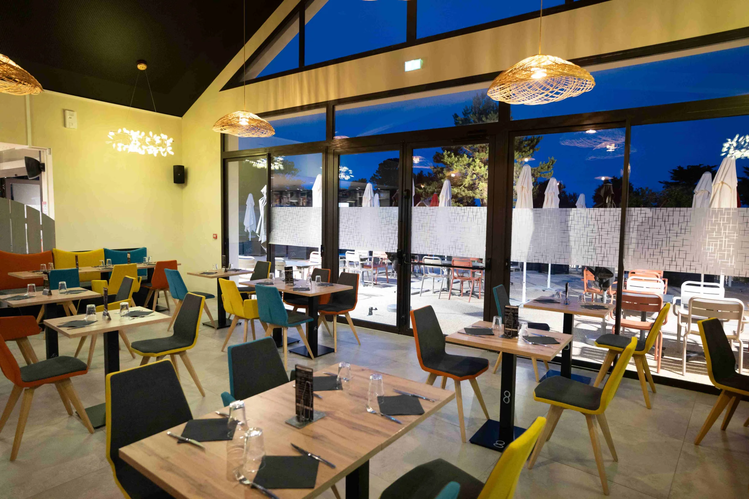 Salle de restaurant moderne et colorée avec verrière.