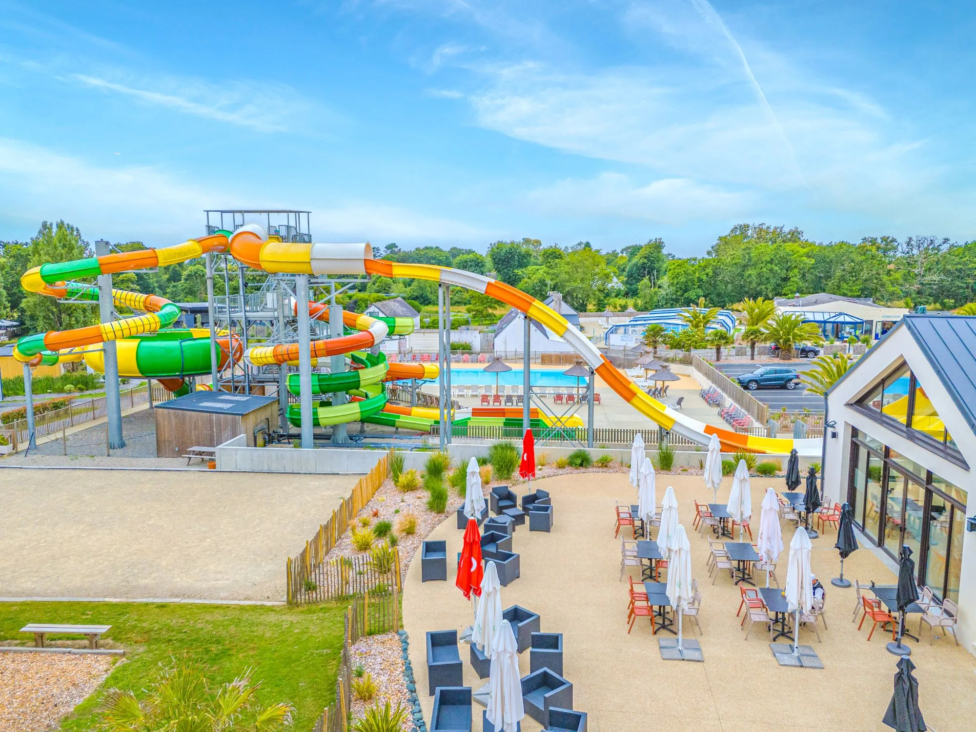 Parc aquatique avec toboggans et terrasse ensoleillée.