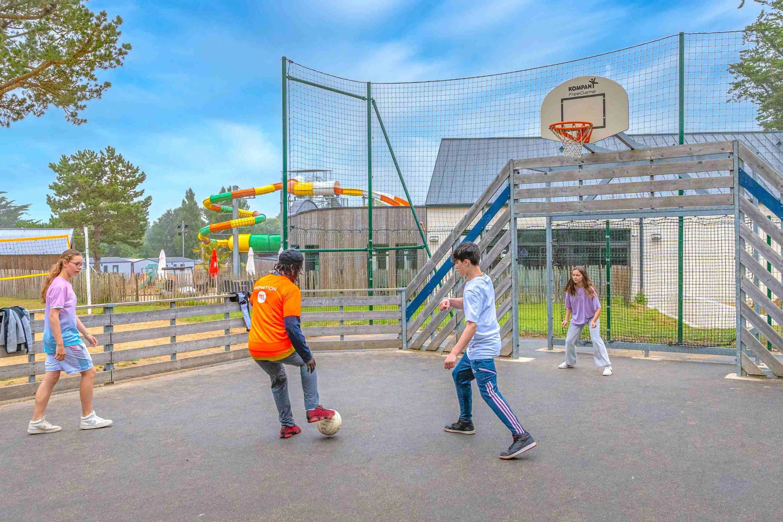 Personnes jouant au foot sur un terrain extérieur.
